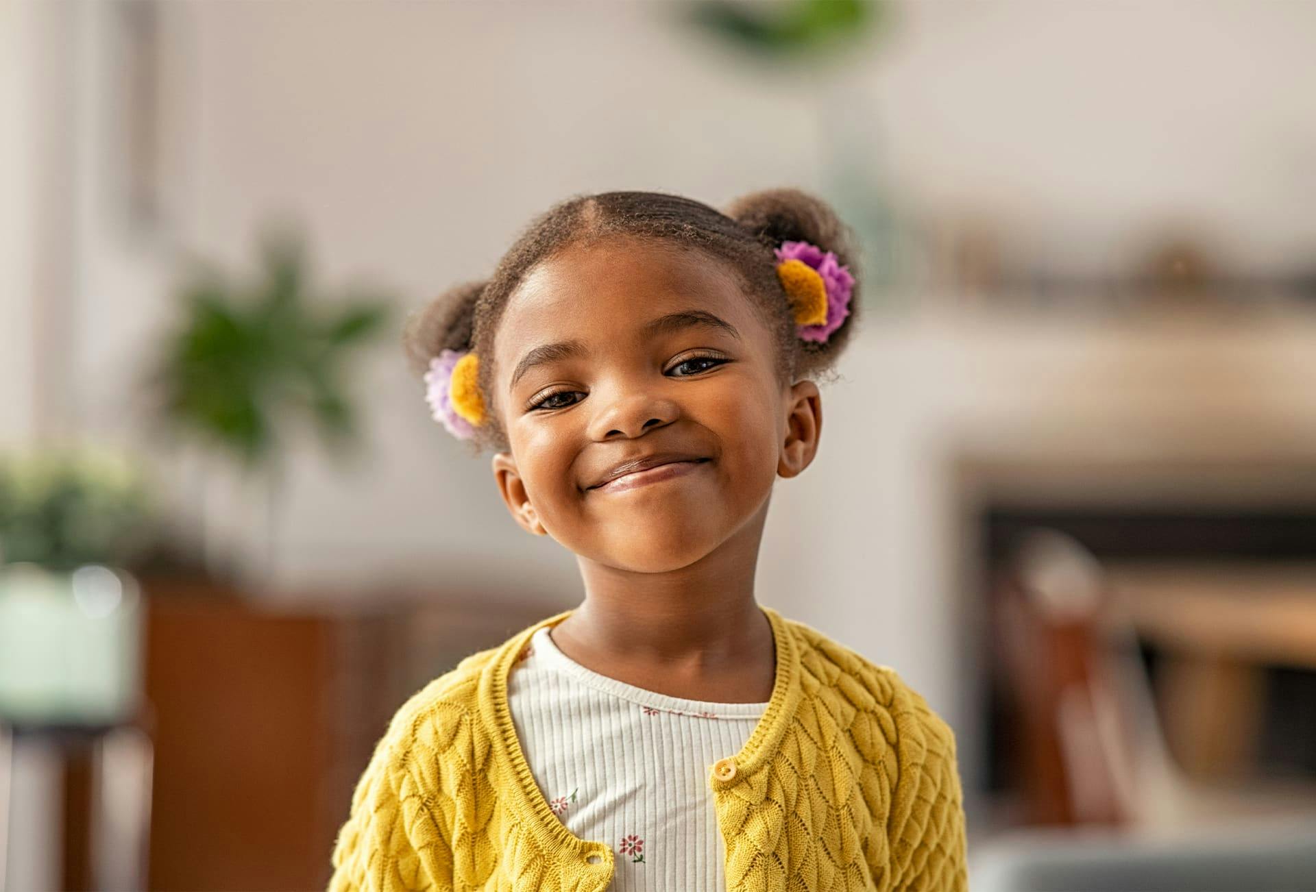 little girl with 2 buns in hair smiling