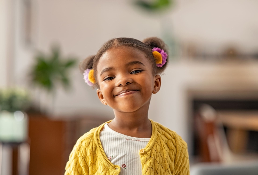 little girl with 2 buns in hair smiling