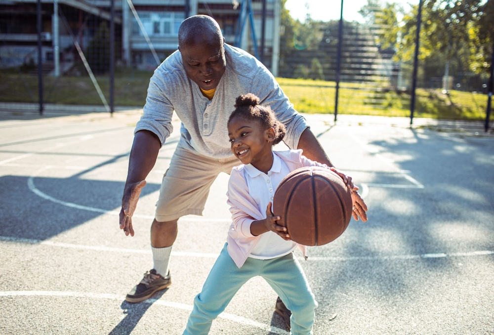 father and daughter playing basketball