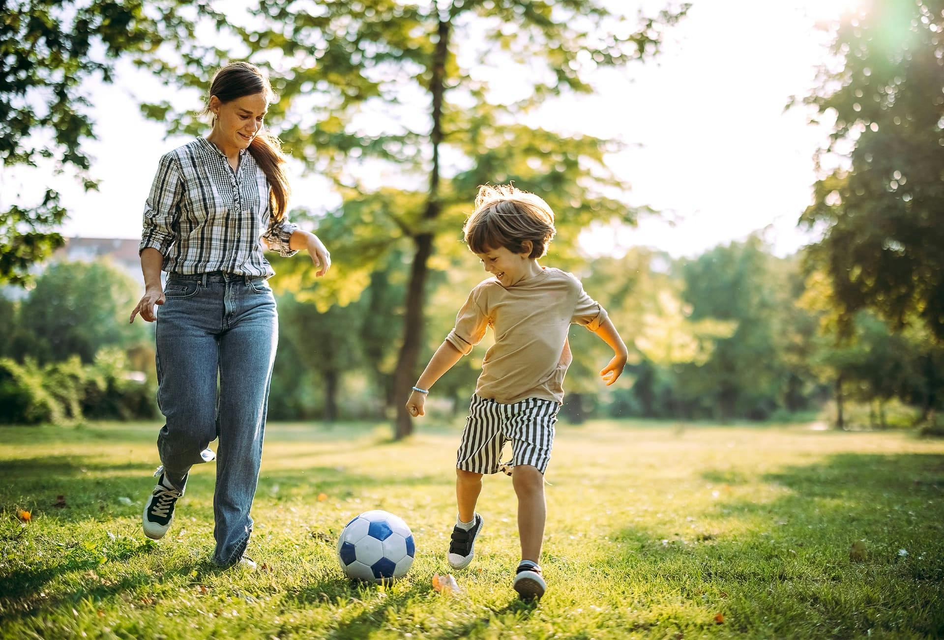 mother and toddler son playing soccer