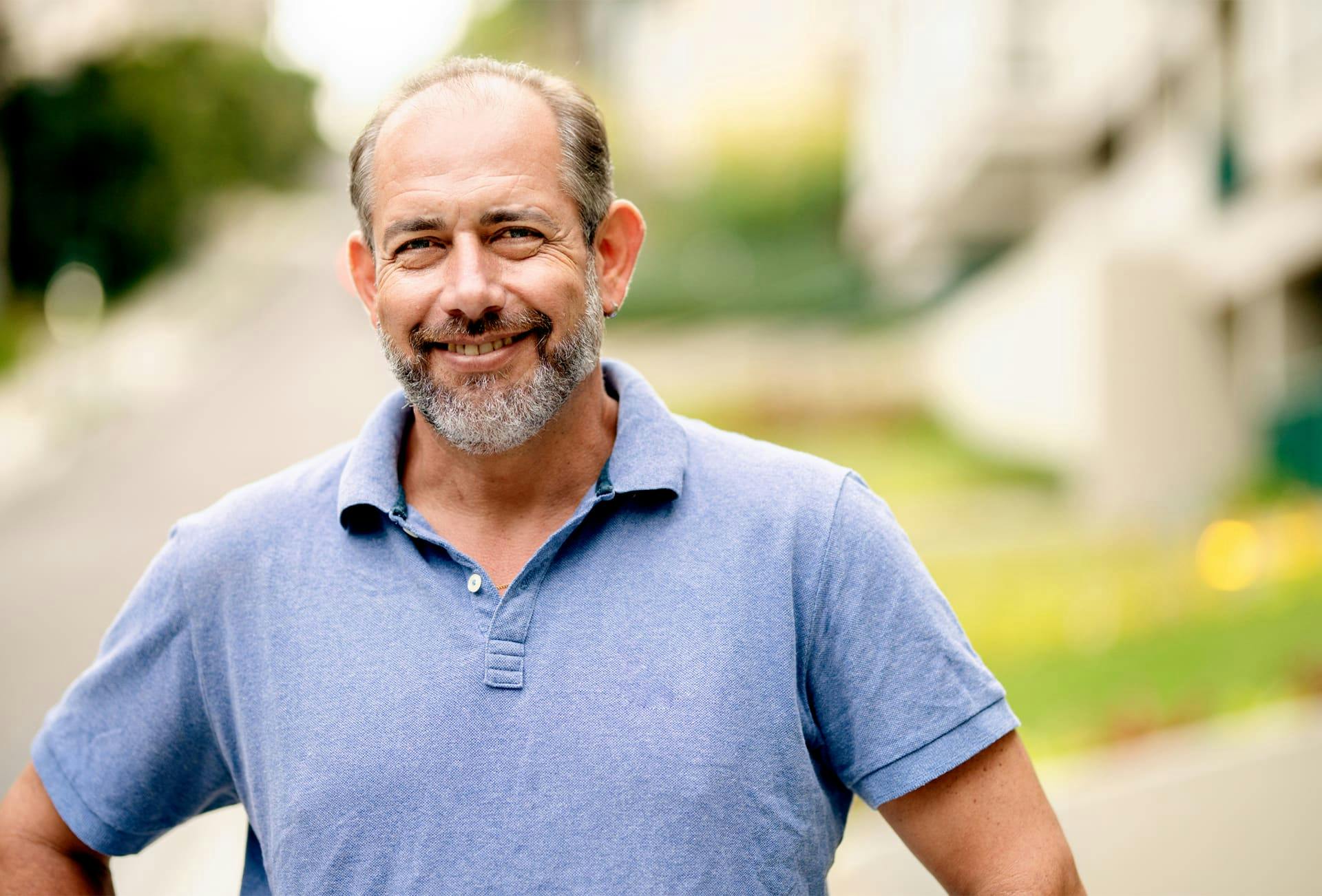 older man with beard with hands on hips smiling