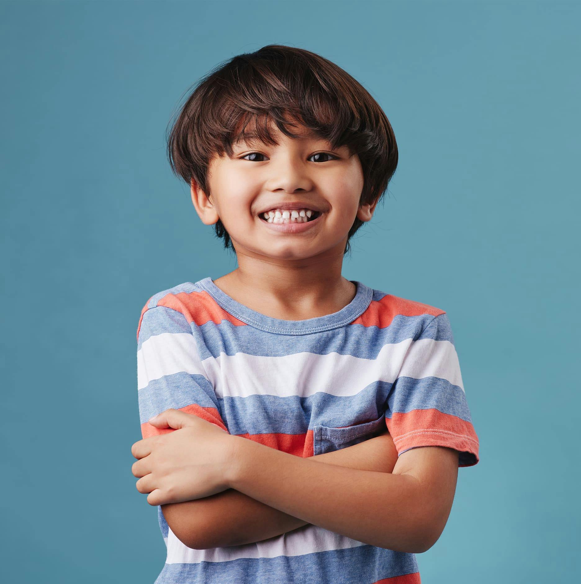 little boy crossing arms smiling with striped shirt