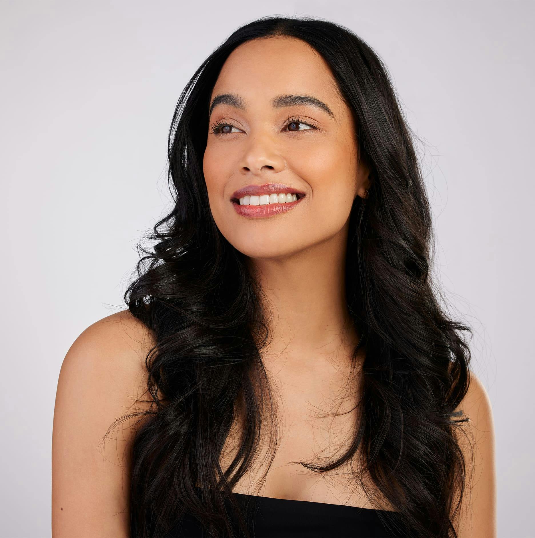 woman with long black hair smiling to the left