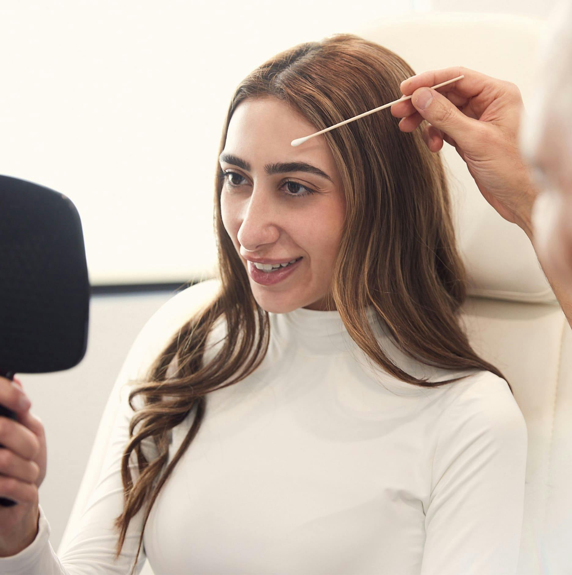 patient holding mirror while Dr. Panossian touching her face with q-tip