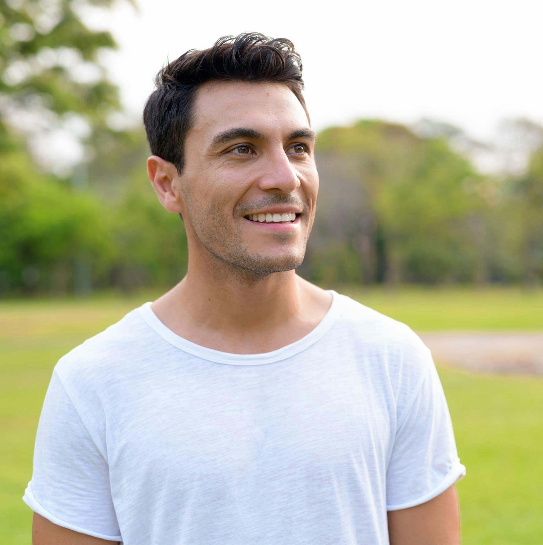 man looking to the right smiling in park