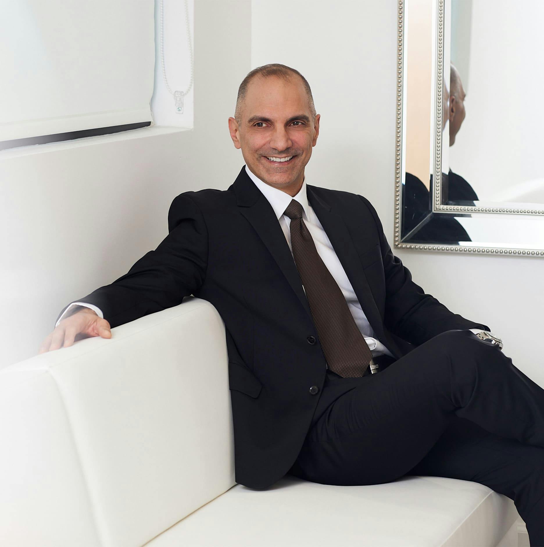 Dr. Panossian sitting on couch in black suit