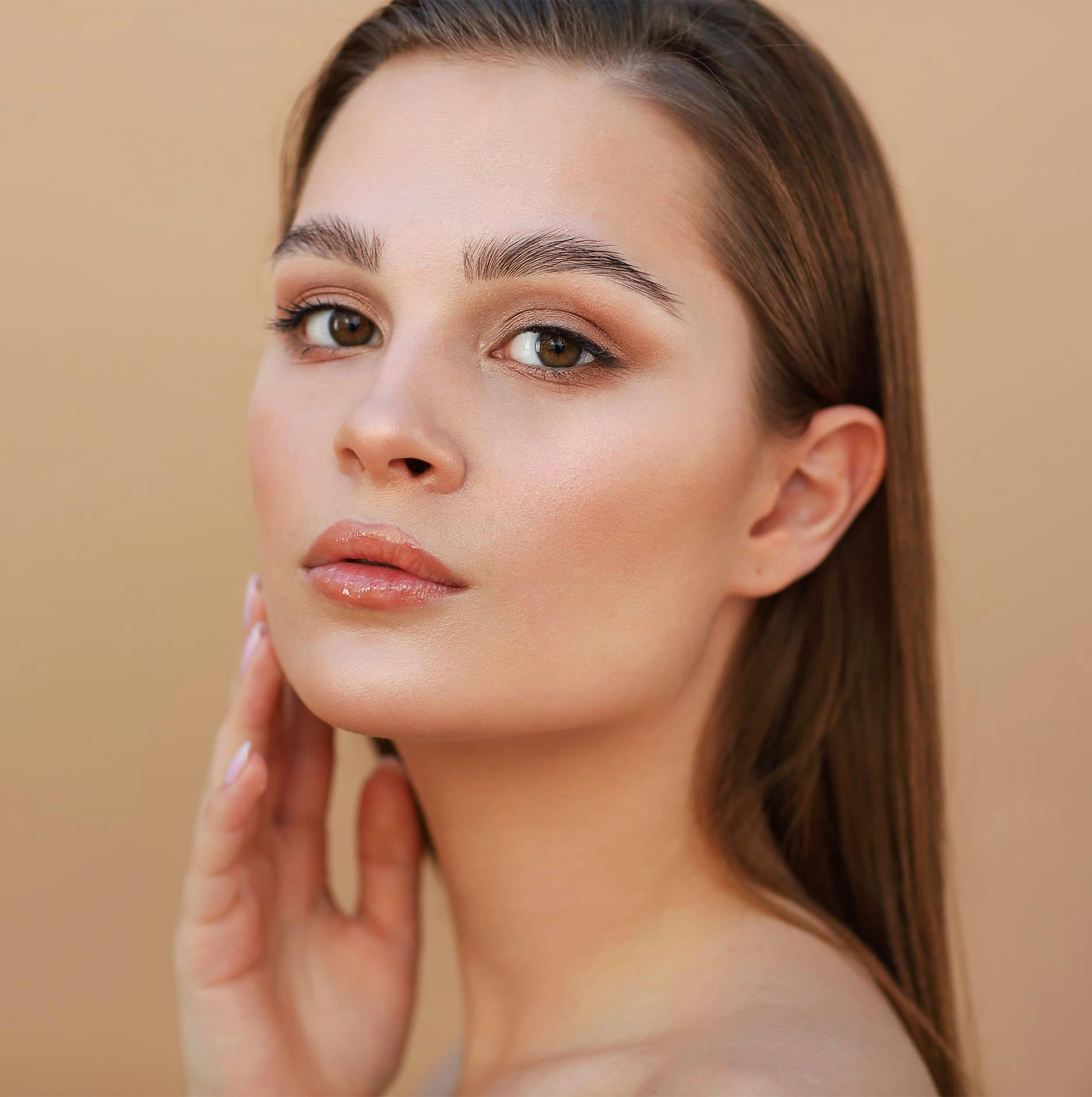 woman with big brown eyes touching jaw facing forward