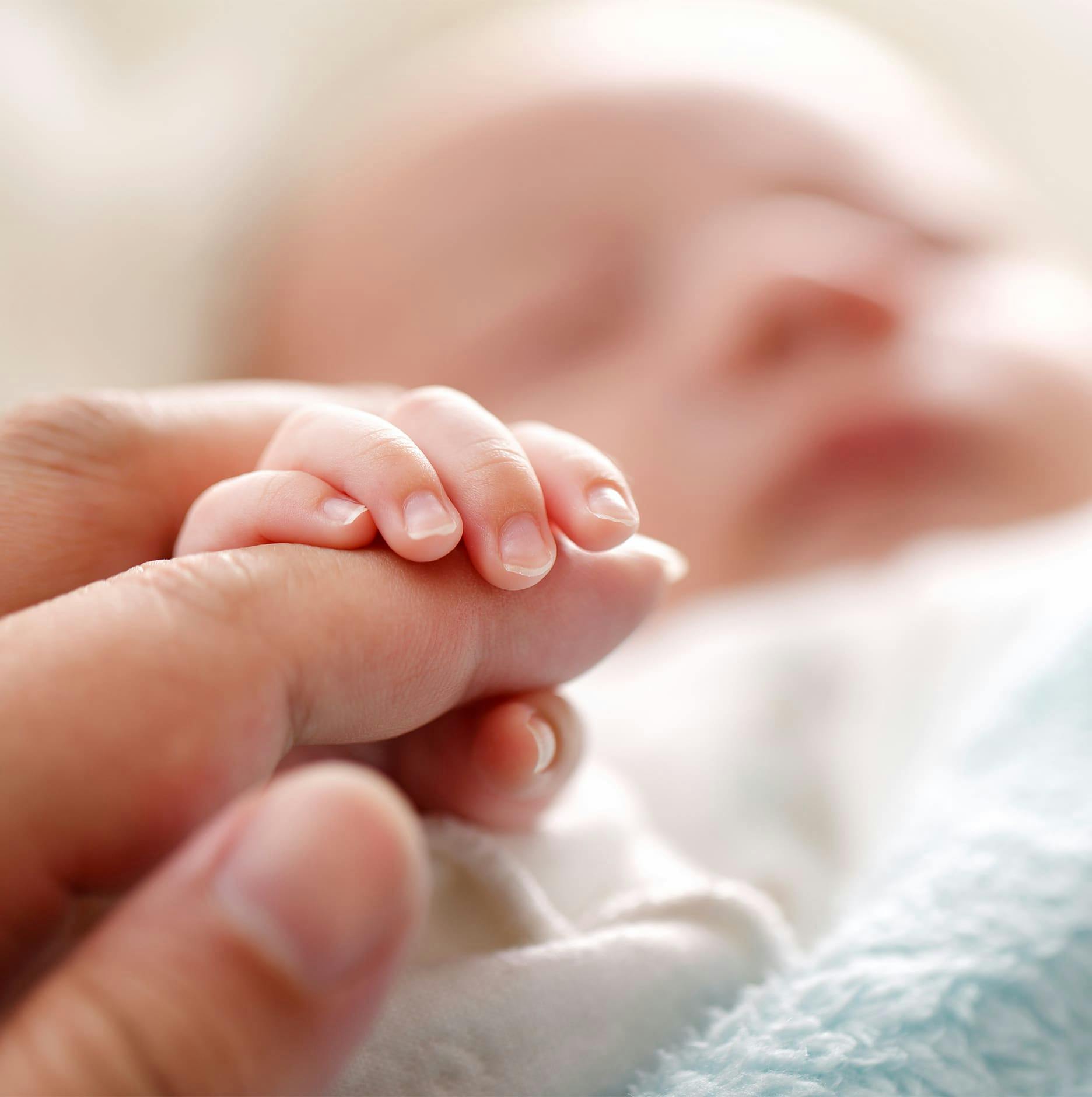 newborn touching an adult's finger