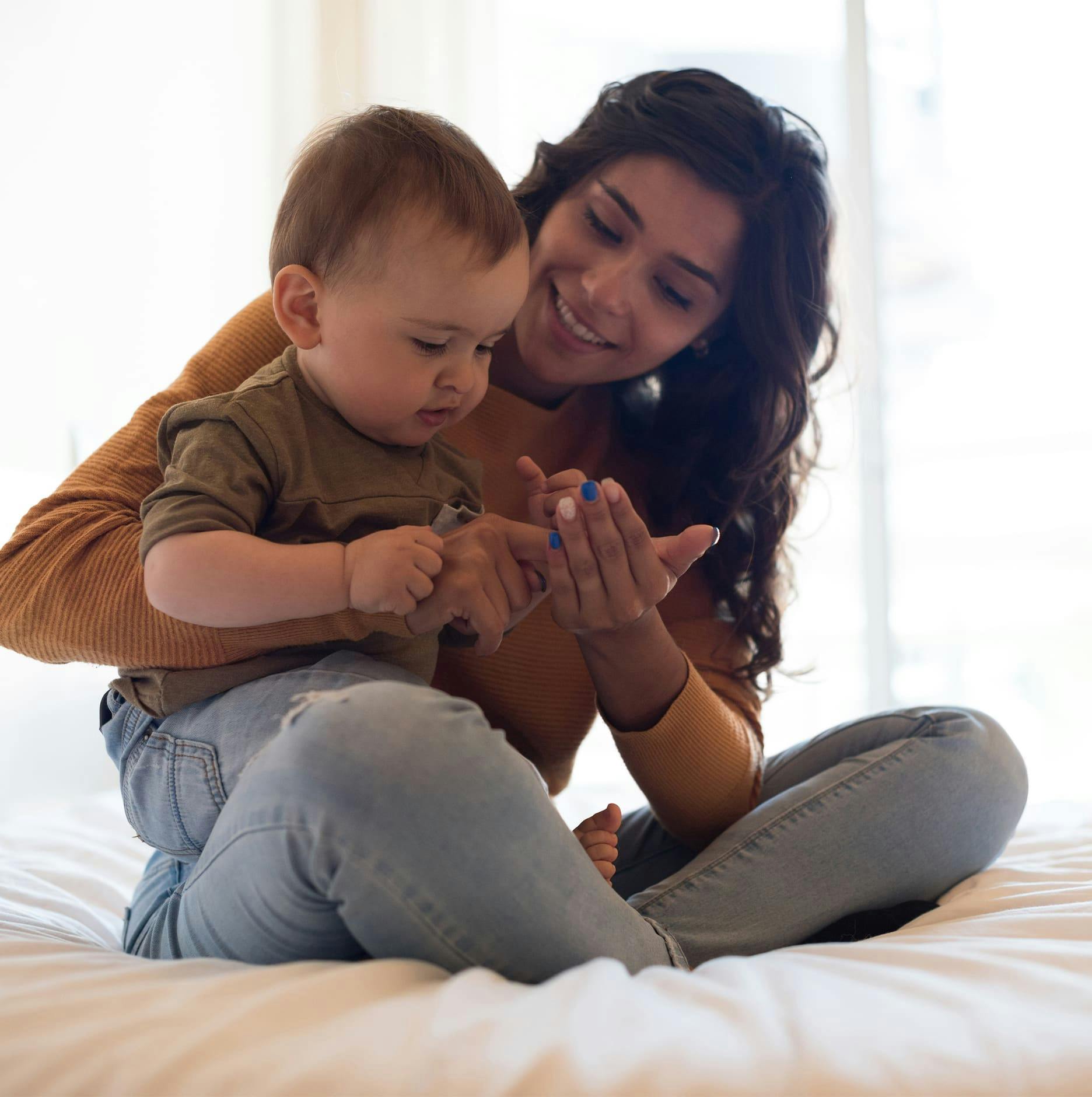mother holding her toddler son on bed