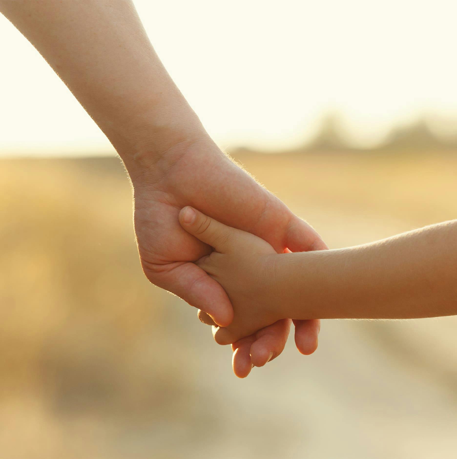 a parent holding their kid's hand
