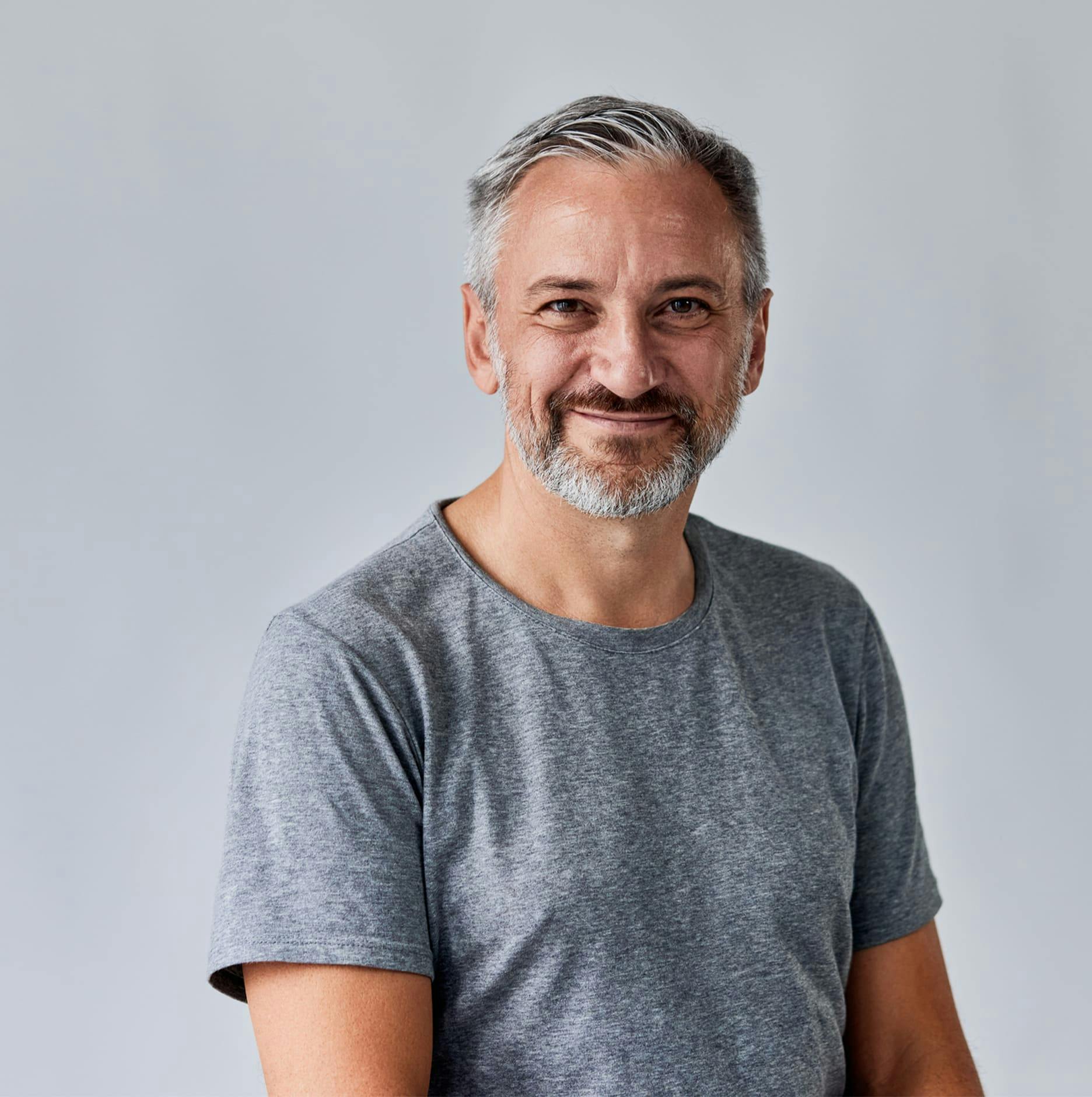 older man smiling in grey shirt