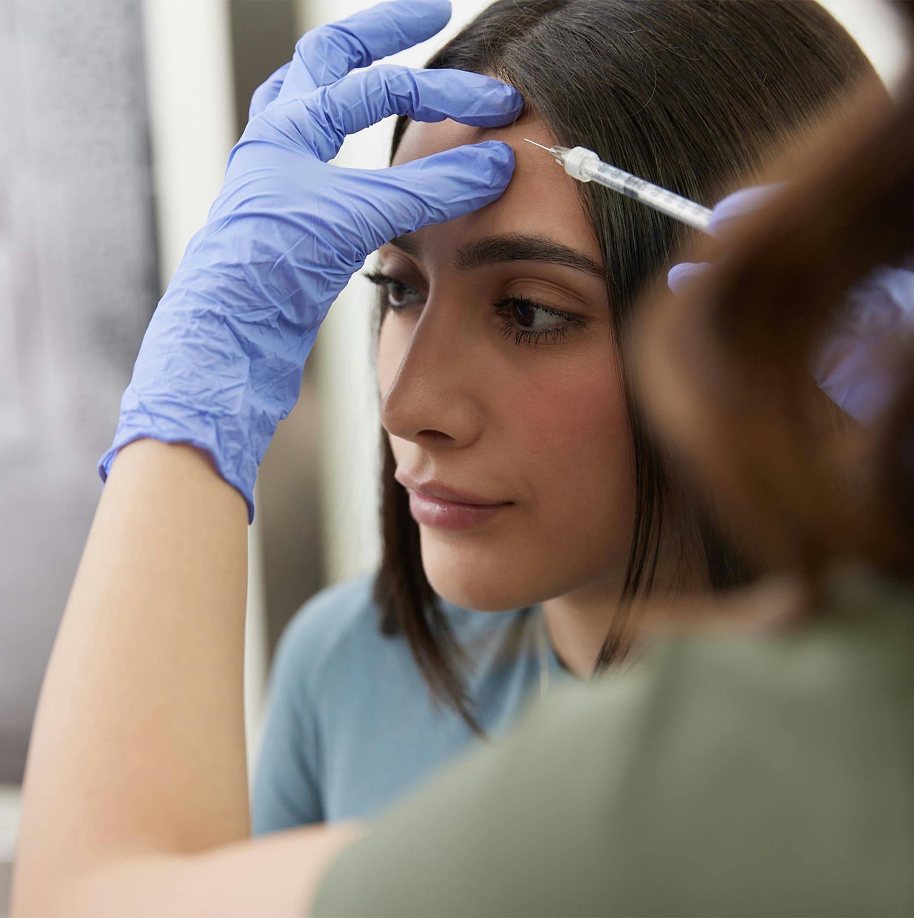 close up of patient with nurse holding syringe at her forehead