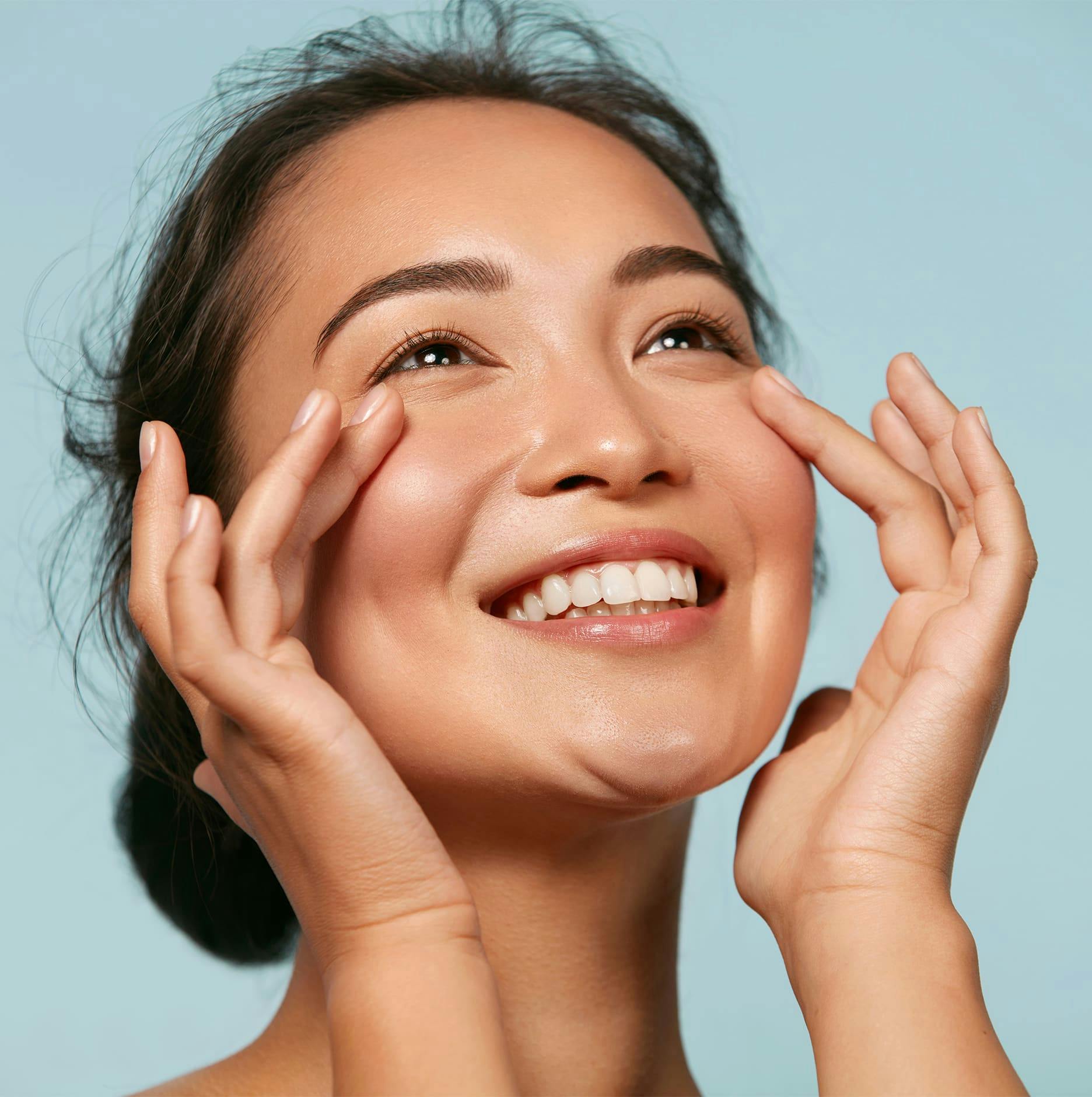 woman looking up while she touches her cheeks