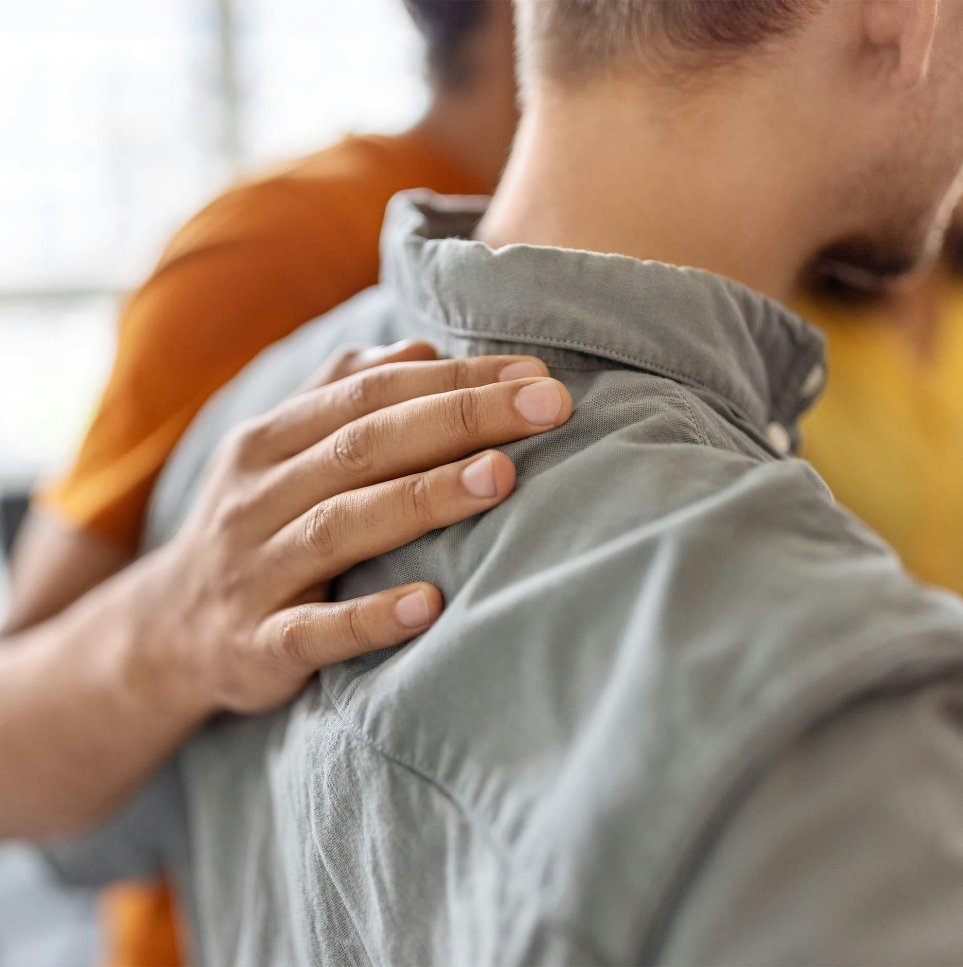 a man touching another man's back during hug