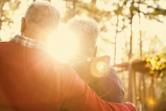 Elderly couple hugging at sunset