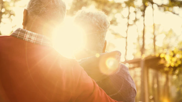 Elderly couple hugging at sunset
