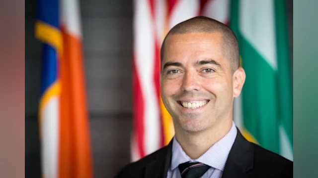 Man smiling in front of flags