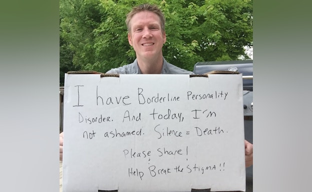 Man holding handwritten sign