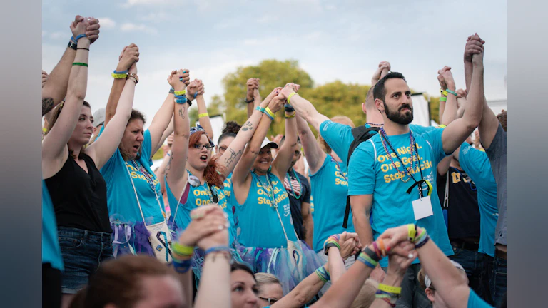 Participants raise their arms together at the Overnight