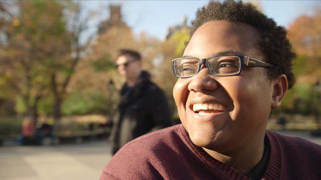 Young adult smiling while sitting in park