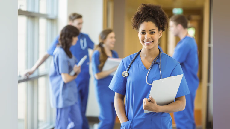 A nurse smiling as she walks down a  hallway