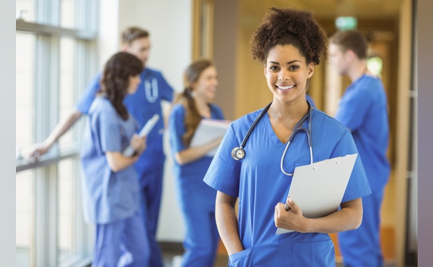 A nurse smiling as she walks down a hallway