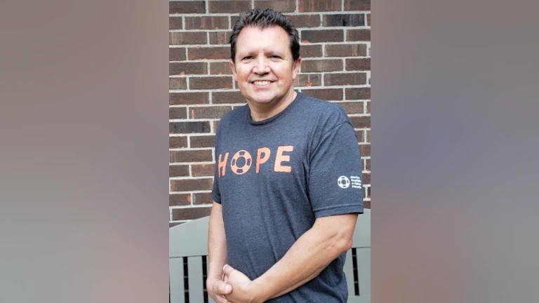 Man smiling in front of brick wall