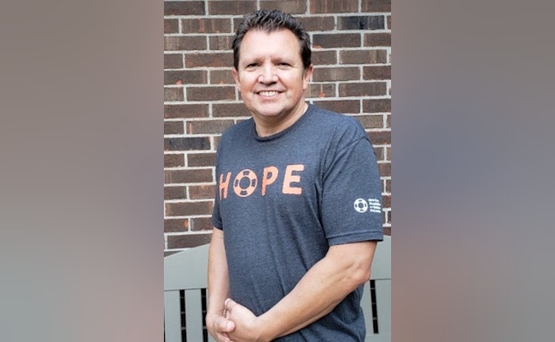 Man smiling in front of brick wall