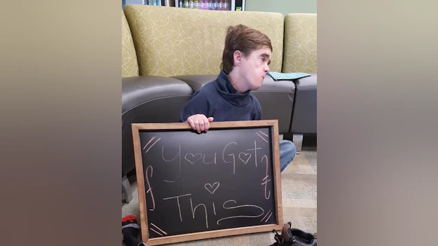 person holding chalkboard with inspirational saying