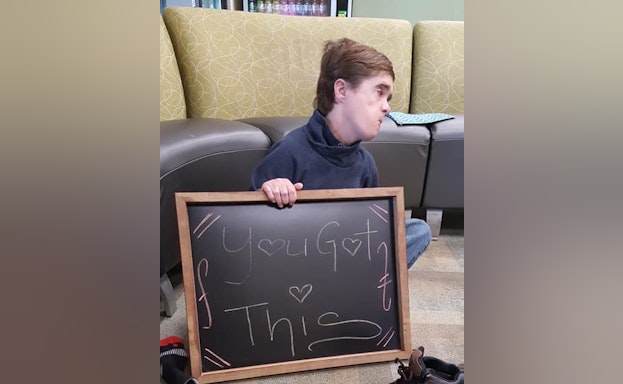 person holding chalkboard with inspirational saying