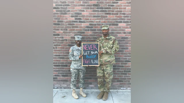Man and woman in fatigues holding chalkboard