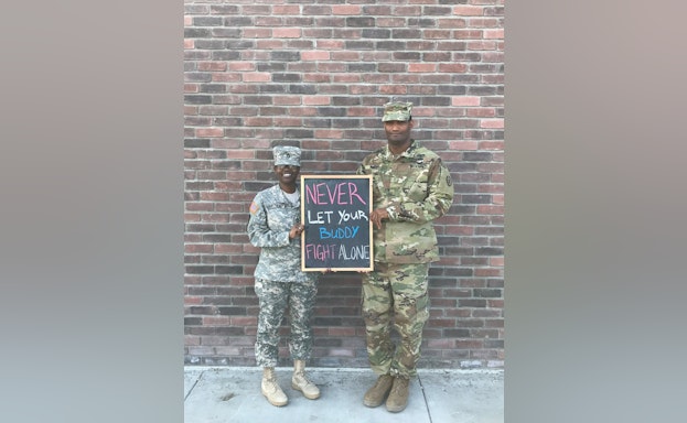 Man and woman in fatigues holding chalkboard
