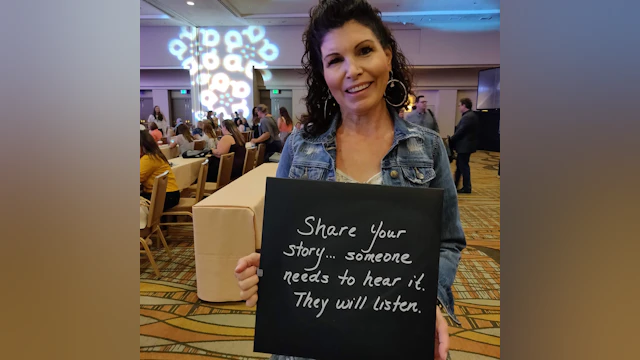 Woman in banquet hall holding chalkboard