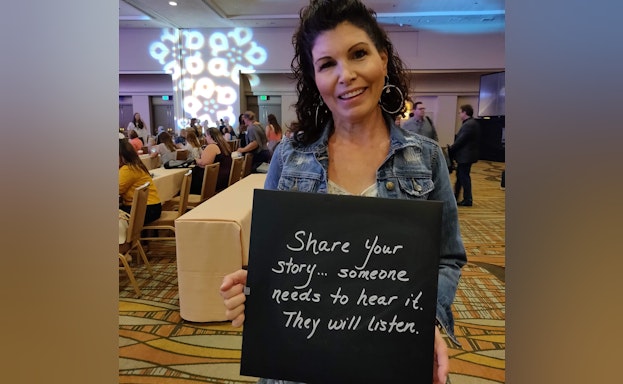Woman in banquet hall holding chalkboard