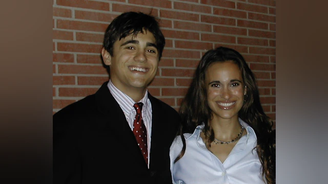 Man and woman smilng in front of brick wall