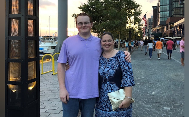 Kathe standing beside her son with her arm around him.