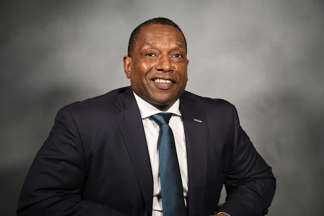 Photo of Victor Armstrong wearing a suit and smiling at the camera