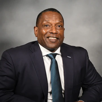 Photo of Victor Armstrong wearing a suit and smiling at the camera
