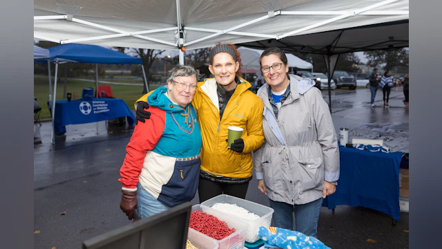 Three women standing under a tent