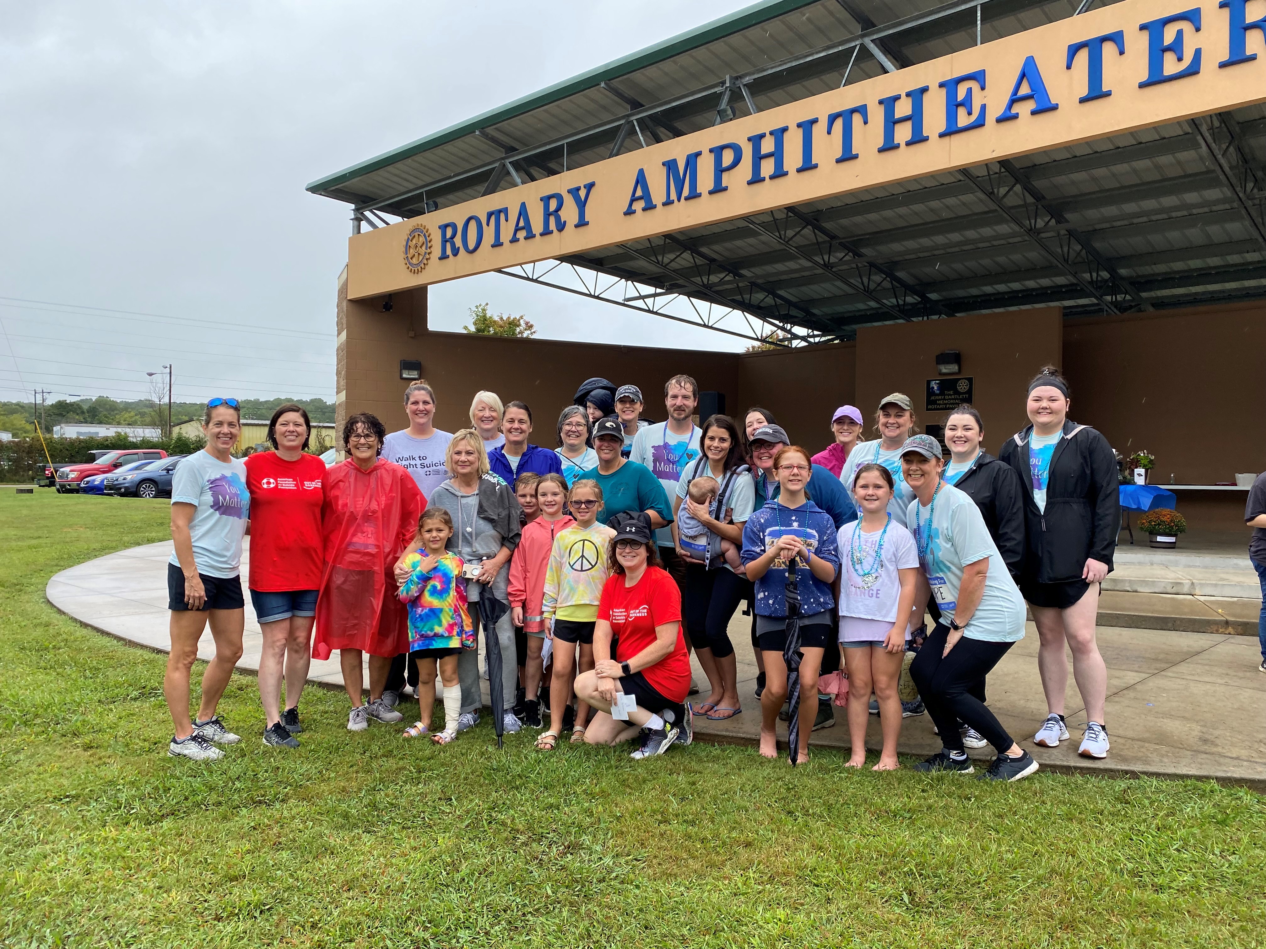 A gruop of people pose for a photo in front of an ampitheater.