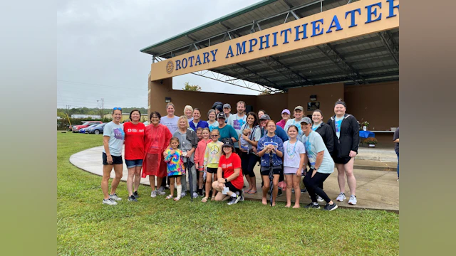 A gruop of people pose for a photo in front of an ampitheater.