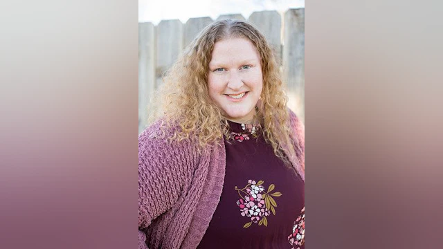 Woman smiling and wearing a burgandy blouse and cardigan