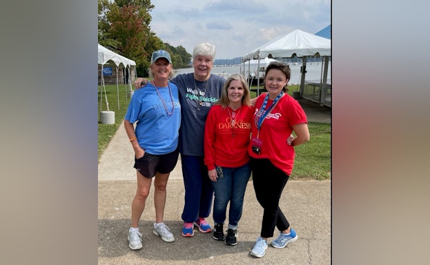 Walkers stand side by side in front of a body of water.