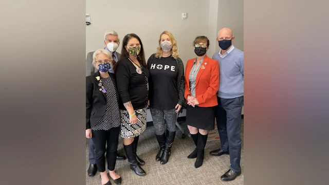 Six people wearing masks stand together for a photograph.