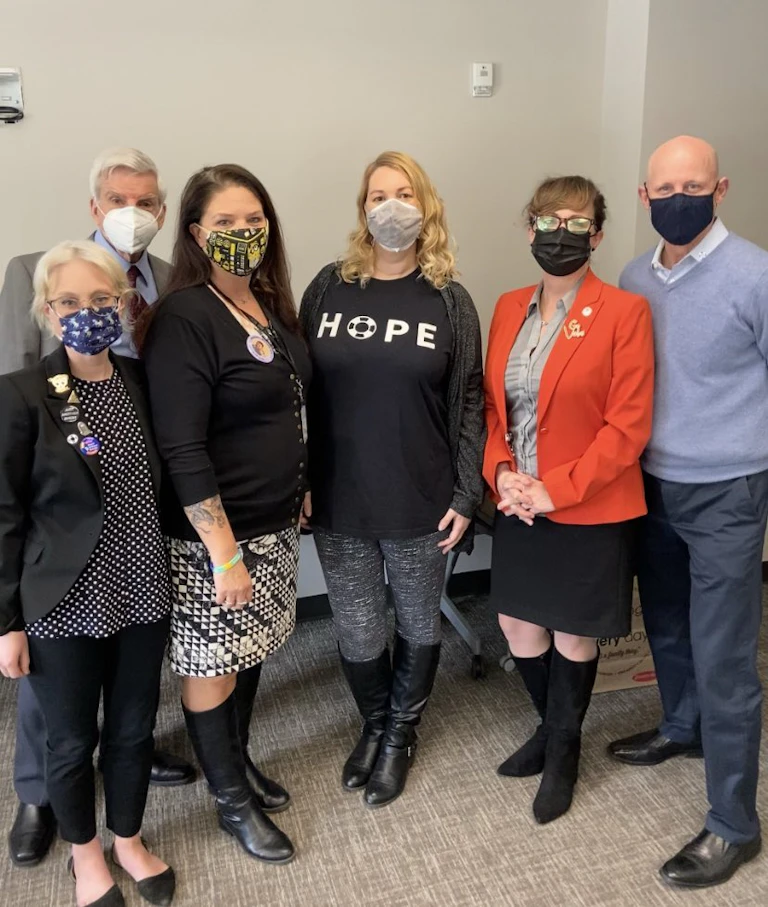Six people wearing masks stand together for a photograph.