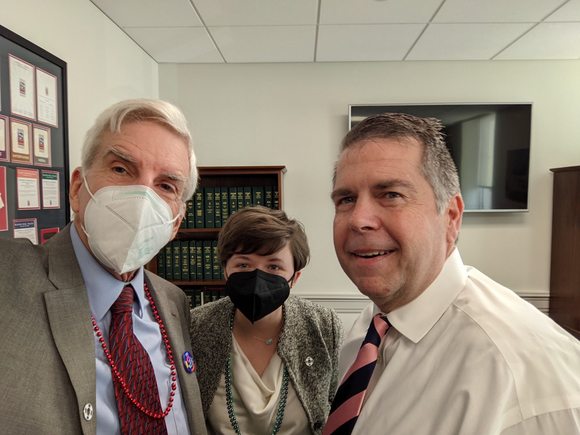 Three people smile for a seflie in an office.