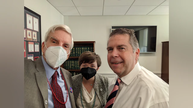 Three people smile for a seflie in an office.