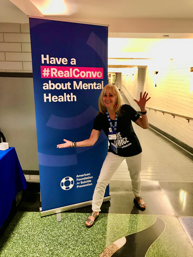 Wendy Sefcik smiling in front of a tall #RealConvo banner