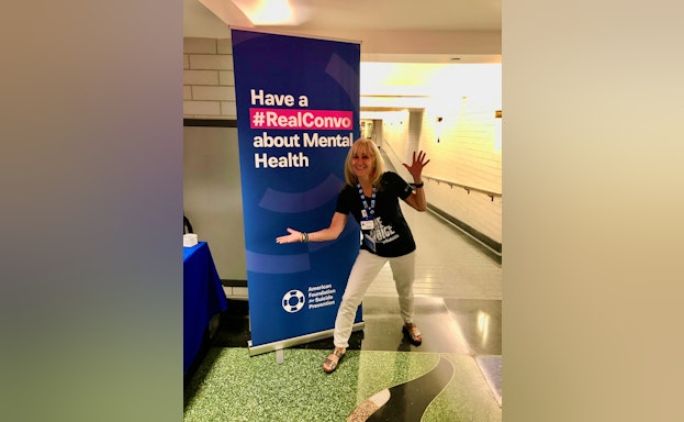 Wendy Sefcik smiling in front of a tall #RealConvo banner