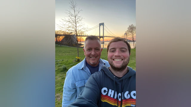 Michael and his father standing in front of a bridge at sunset